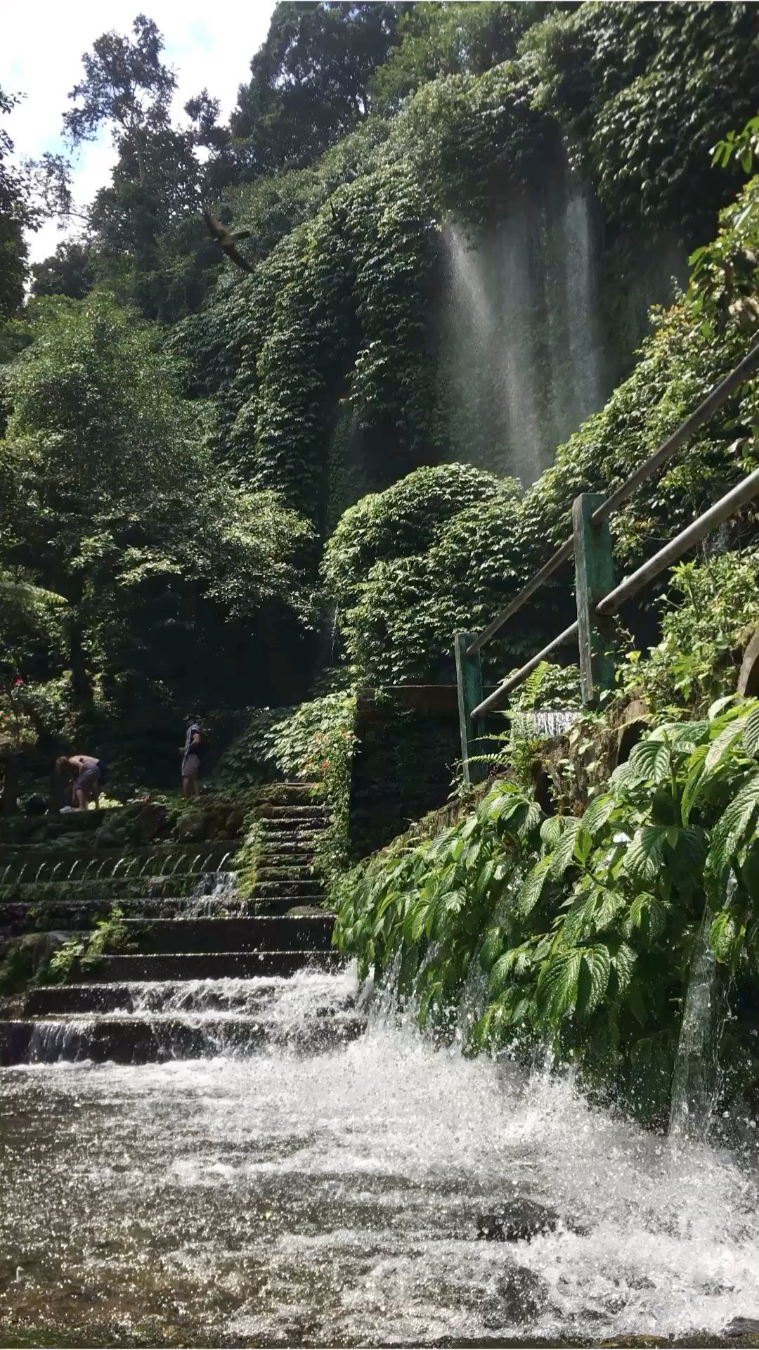 Waterfall flowing down a green cliff in Lombok.