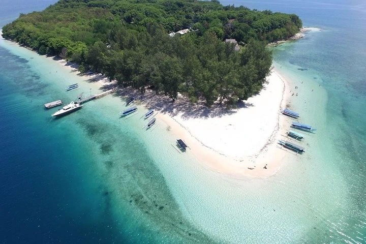 Boats on clear shallow water off a small island beach, Gili Nanggu